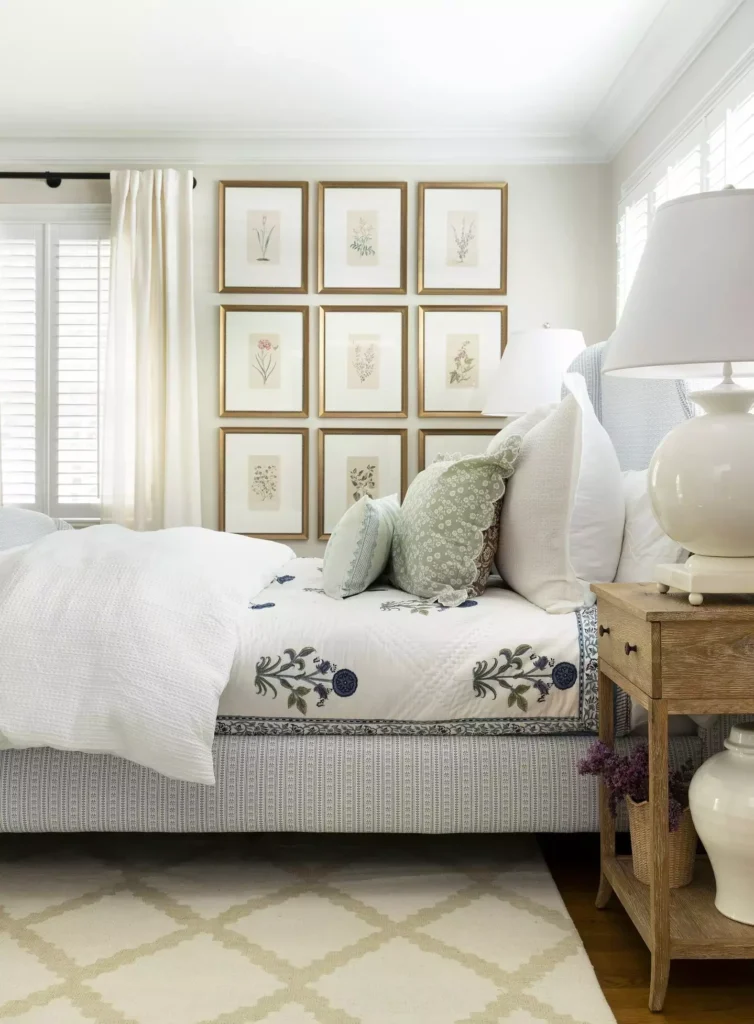 Grid of nine framed botanical prints used as over the bed wall decor above a white bed