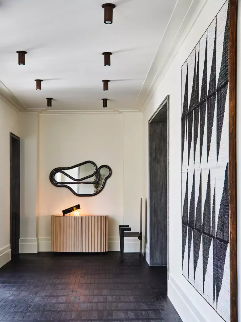 Hallway wall featuring a sculptural squiggle mirror and a graphic woven wall hanging