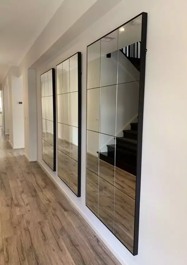 11. Hallway wall lined with oversized black framed mirror panels