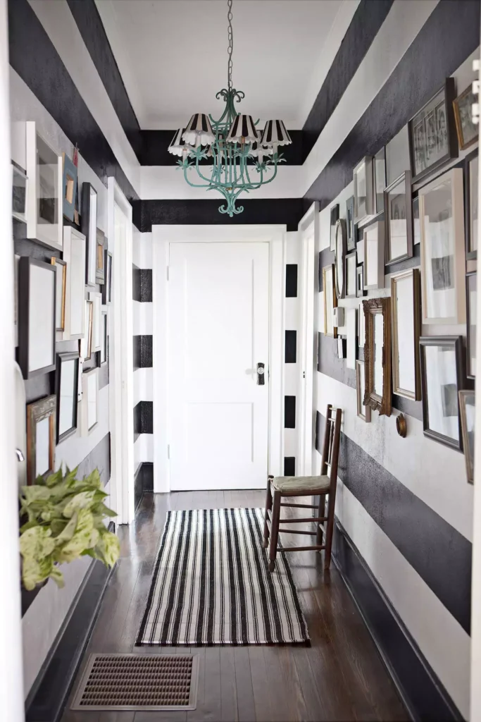 Hallway wall striped in bold black and white with a dense vintage frame gallery