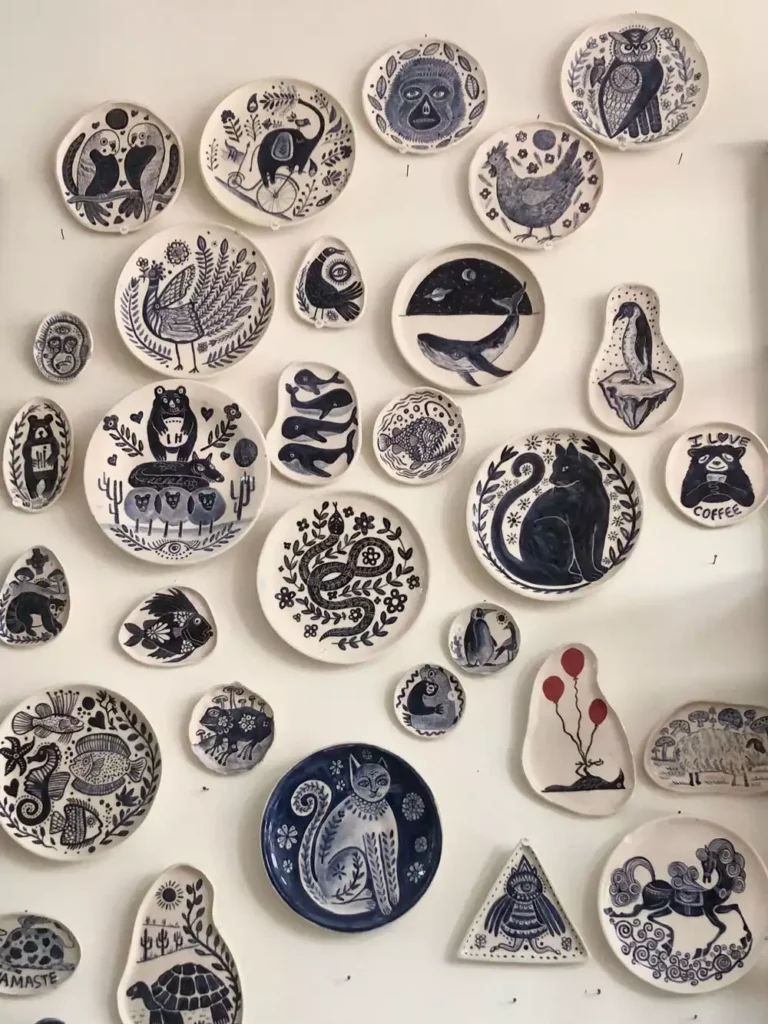 Hand-painted plate wall decor featuring animal and folk art designs in black and white