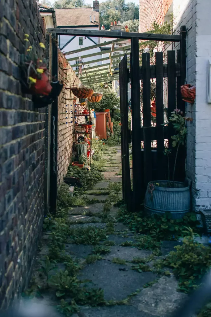 Hanging Planters Lining A Narrow Outdoor Brick Wall Alley