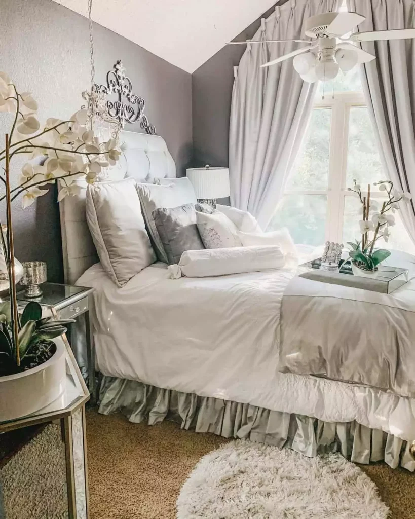 Hollywood glam grey bedroom wall with an ornate scroll mirror and ruffled bedding