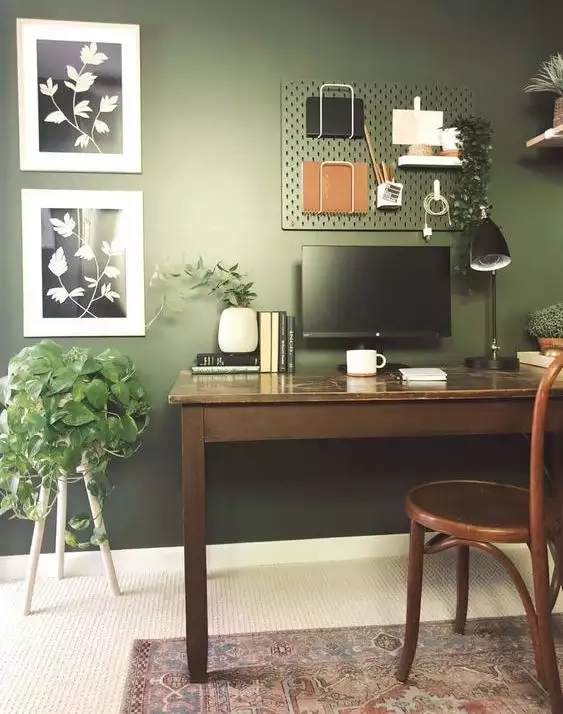 Hunter green wall office with a pegboard organizer and botanical prints