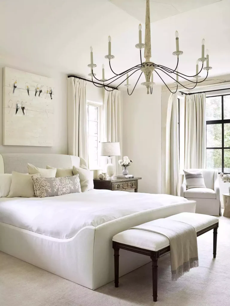 Ivory white bedroom, candle chandelier, upholstered bed, dark bench, bird canvas