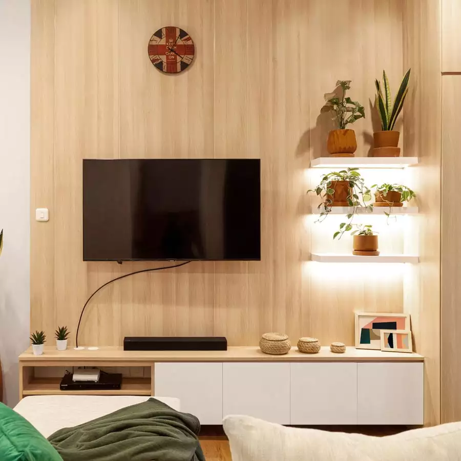 Light Wood TV Wall With Floating Plant Shelves And White Storage Cabinets