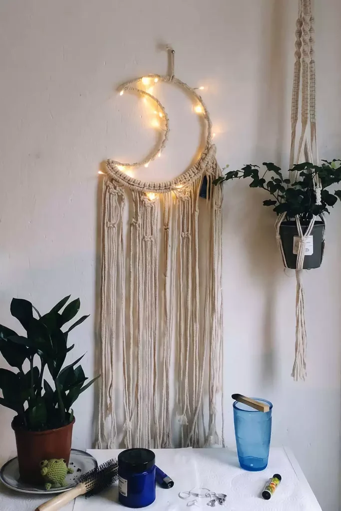 Macrame crescent moon wall hanging with fairy lights beside a macrame plant hanger as easy aesthetic DIY room decor