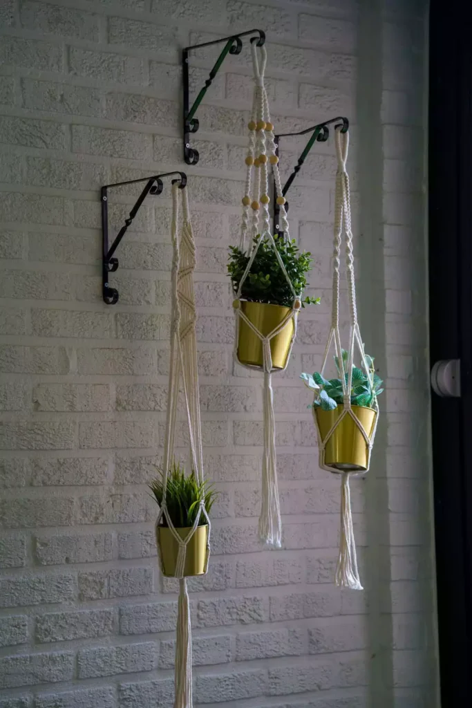 Macrame Plant Hangers Suspended Along A White Brick Wall