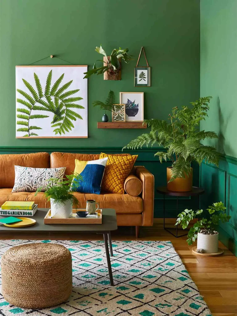  Midcentury living room with rich green walls, tan leather sofa, and fern prints
