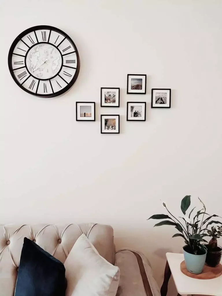 Minimalist Wall With A Black-Framed Round World Map Clock And A Cluster Of Small Black-Framed Photos Above A Tufted Sofa
