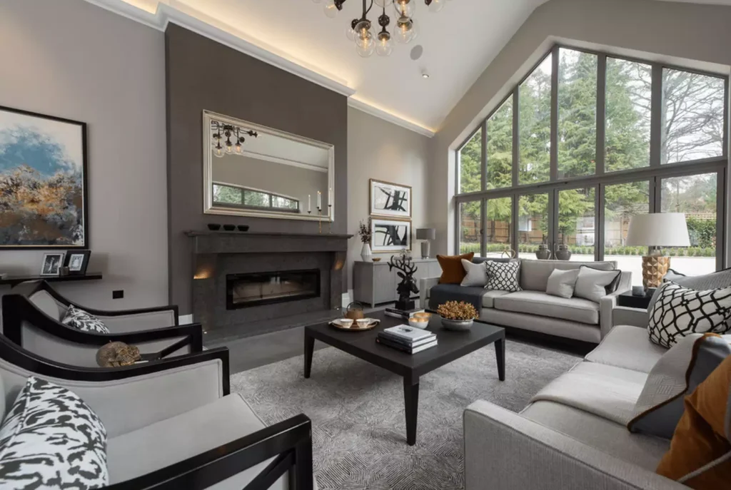 Modern grey living room with vaulted ceiling, floor to ceiling windows and stone fireplace wall