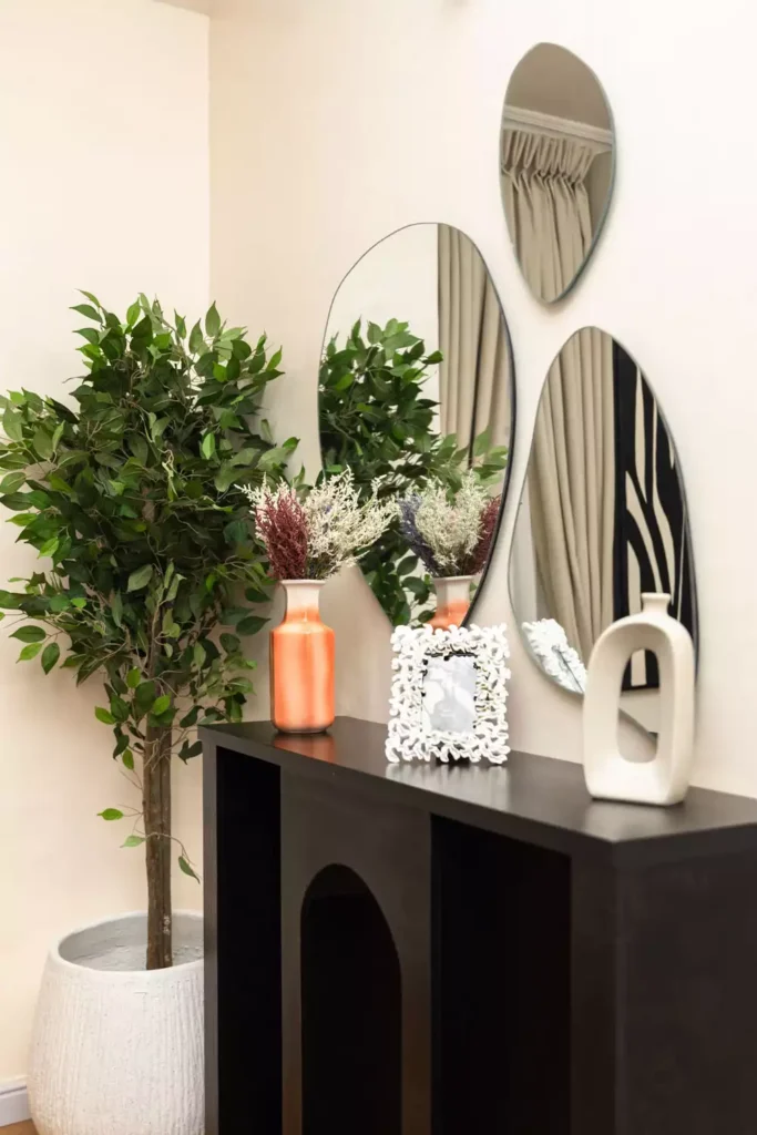 Modern organic entryway decor with black arch console table, sculptural oval mirrors and terracotta vases