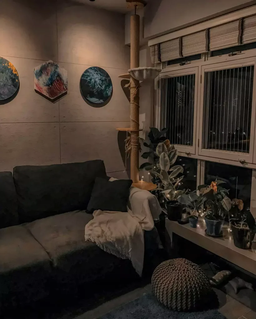 Moody living room corner with dark gray sofa cat tree and warm fairy lights at night