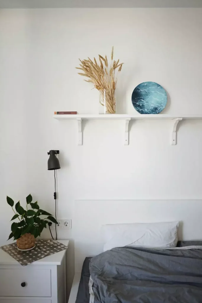 Ocean-inspired art plate on a floating shelf as coastal over the bed wall decor