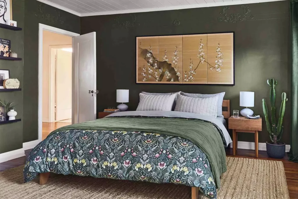  Olive green walls around a floral-bed bedroom with twin lamps and a cactus
