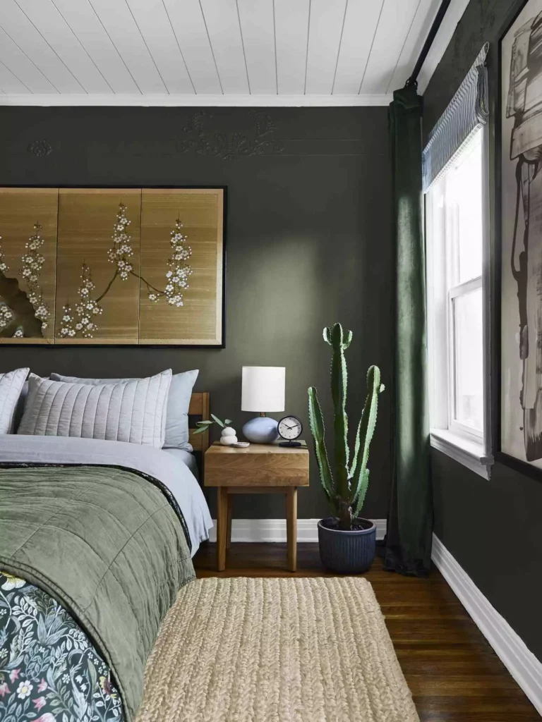 Olive green walls in a bedroom with blossom art, cactus, and a green quilt