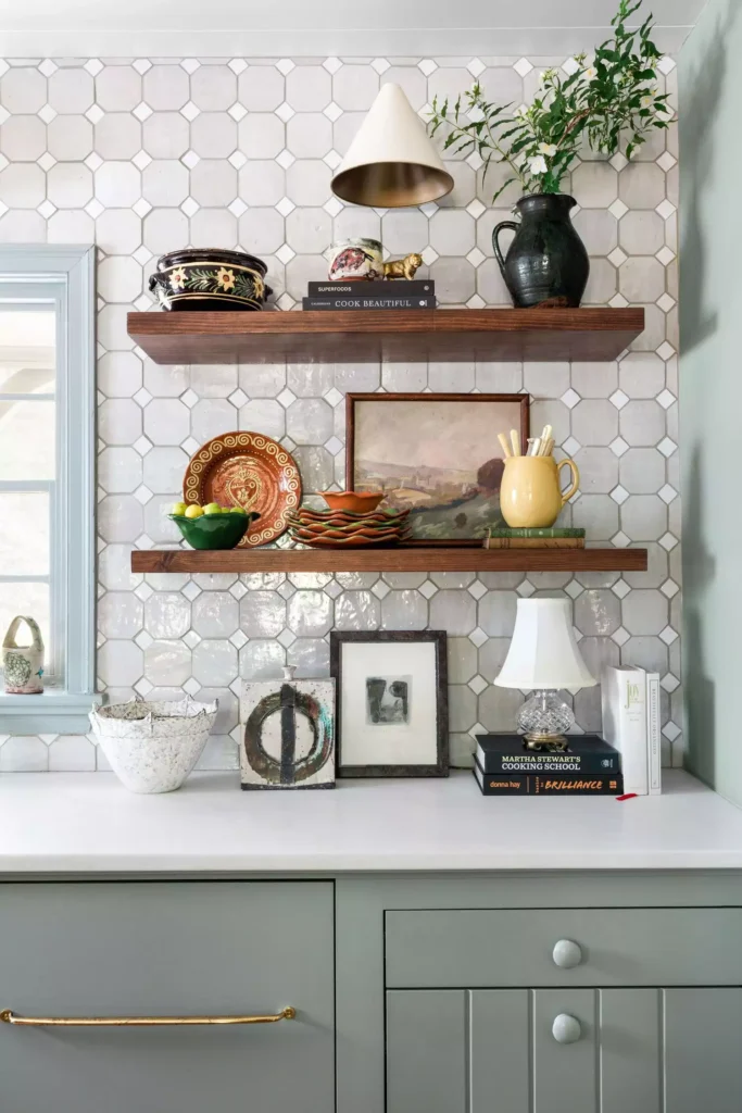 Open wood shelves on patterned tile kitchen wall with plates, art, and cookbooks