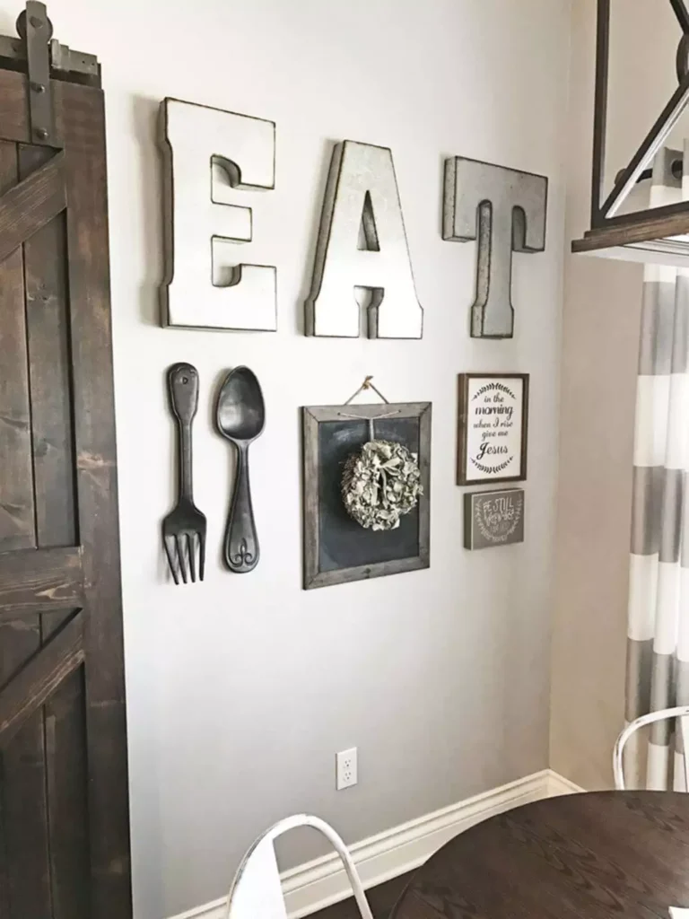 Oversized EAT letters with vintage utensils and framed signs on a kitchen wall