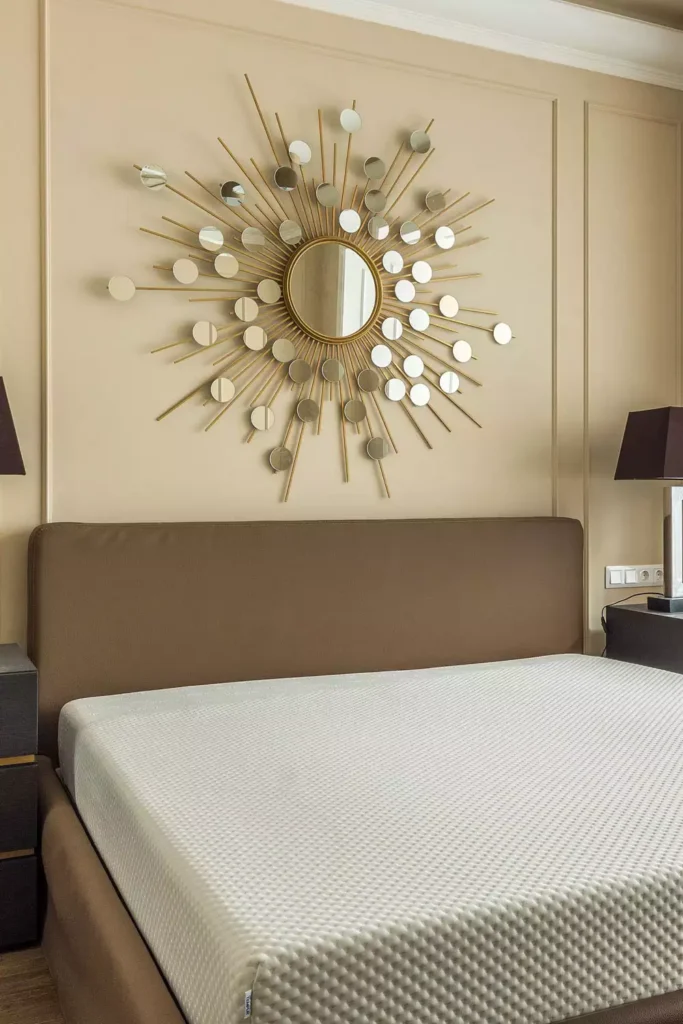 Oversized gold sunburst mirror used as glamorous over the bed wall decor