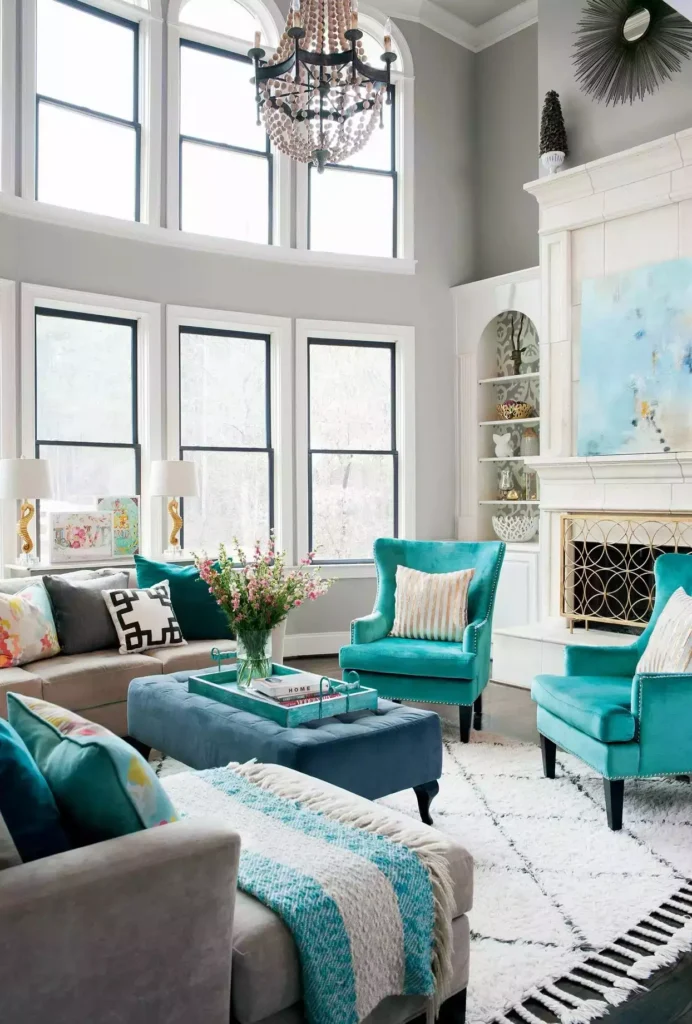 Pale gray-white walls, teal wing chairs, bead chandelier, tall windows