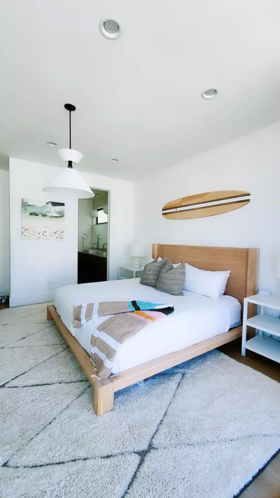 Plain White Bedroom With A Wood Dresser And Surfboard Accent