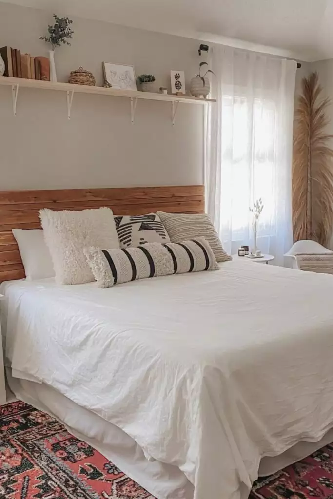 Reclaimed wood shelf with layered art and greenery as farmhouse over the bed wall decor