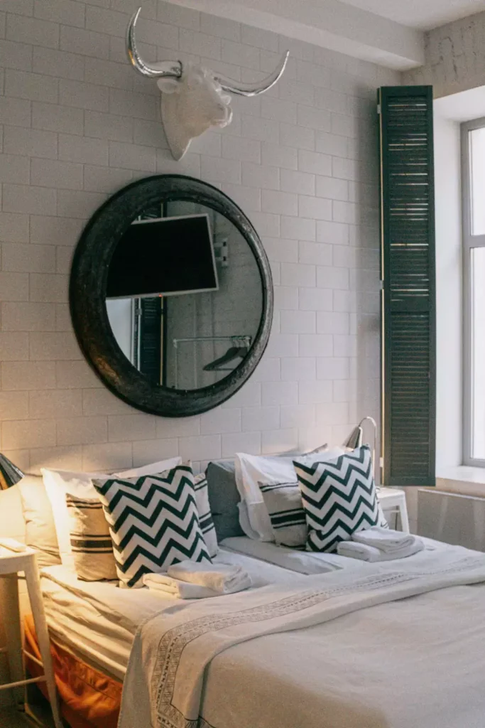 Round mirror with a faux bull skull as eclectic over the bed wall decor