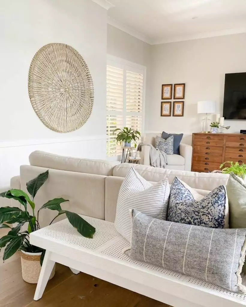 Round woven rattan wall art above coastal-style living room sofa