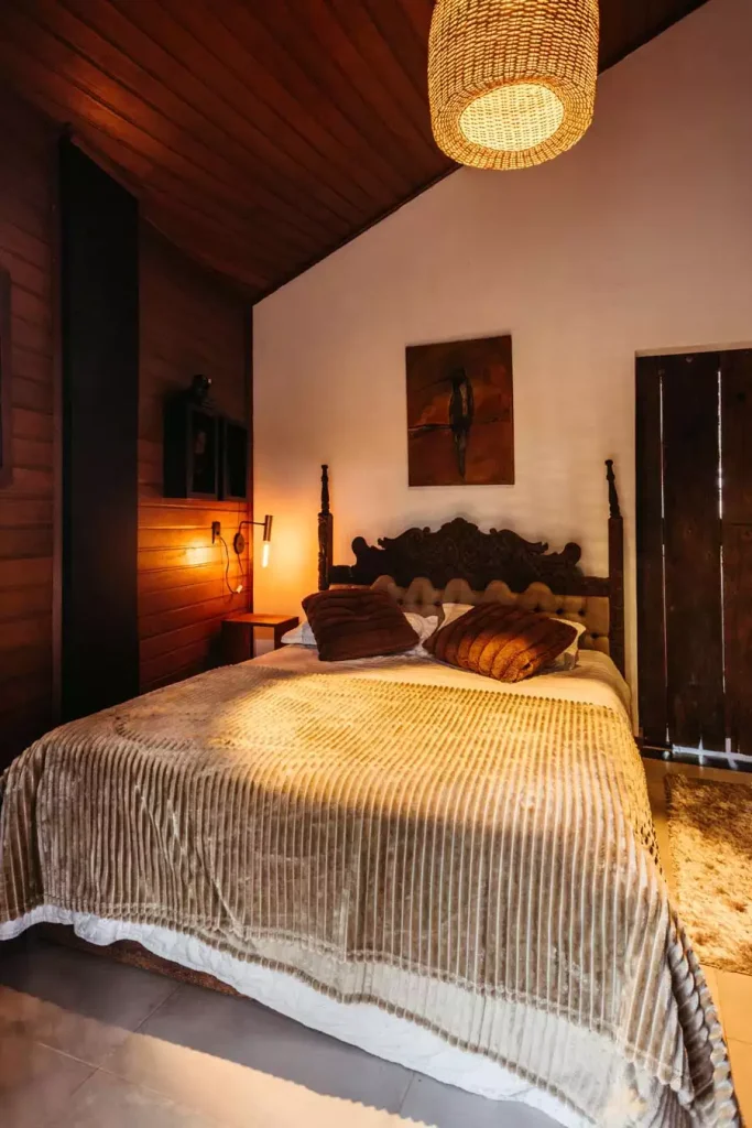 Rustic Wall Decor For A Small Bedroom With Warm Wood Paneling And A Carved Wooden Headboard