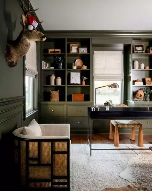 Rustic green wall office with built-in shelving and a mounted deer head accent