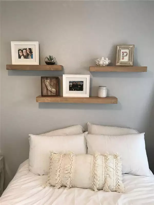 Set of three wood floating shelves styled with frames and decor as over the bed wall decor