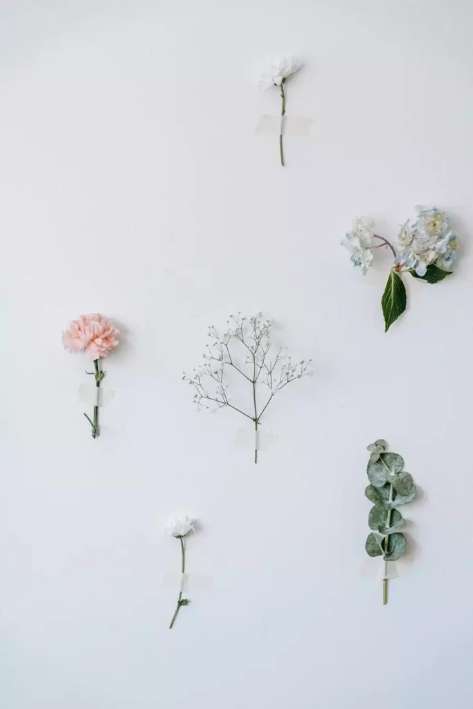 Small flowers and eucalyptus stems taped to a white wall in an easy aesthetic DIY room decor idea