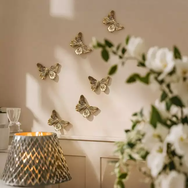 Small brass Butterfly Wall cluster catching sunlight near blush florals
