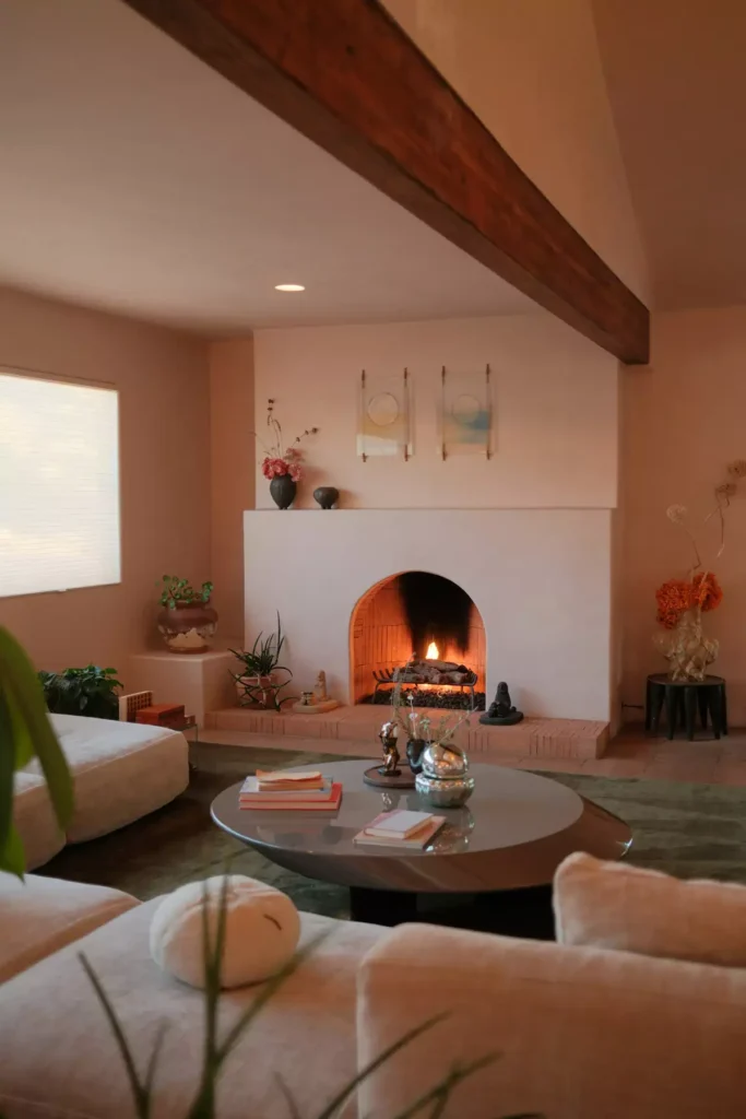 Southwestern-style tan wall living room with an arched fireplace, a wood ceiling beam, and blush velvet sofas
