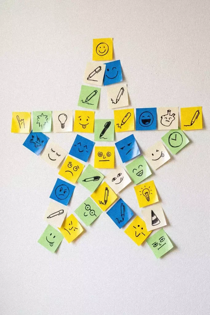 Star Shaped Sticky Notes Wall in Yellow Blue Green and Cream with Hand Drawn Smiley Faces Pens and Light Bulbs