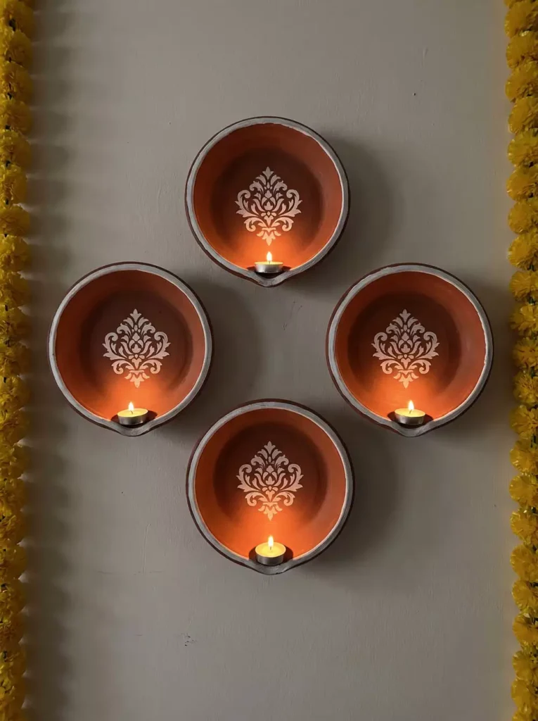 Terracotta diya wall sconces arranged in a diamond, a rustic Diwali wall decor idea