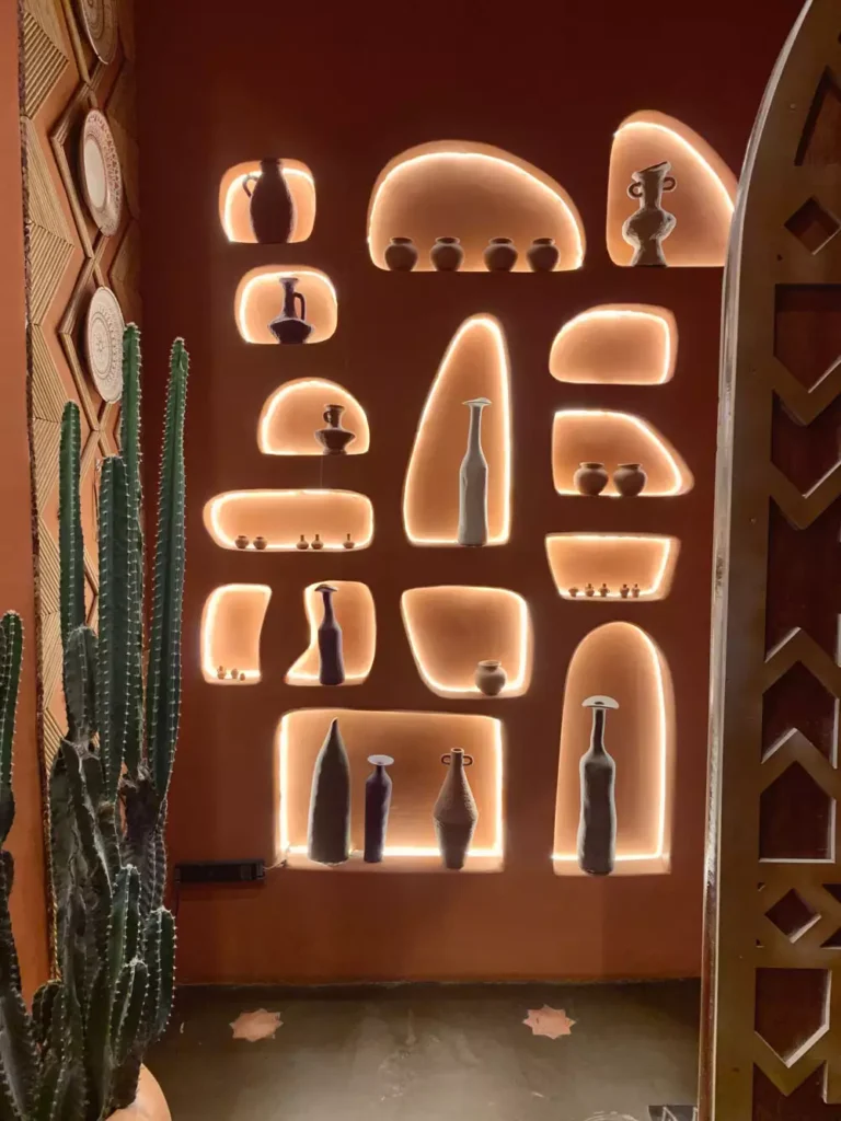 Terracotta Wall Arches Glowing Around Ceramic Vases Beside A Cactus