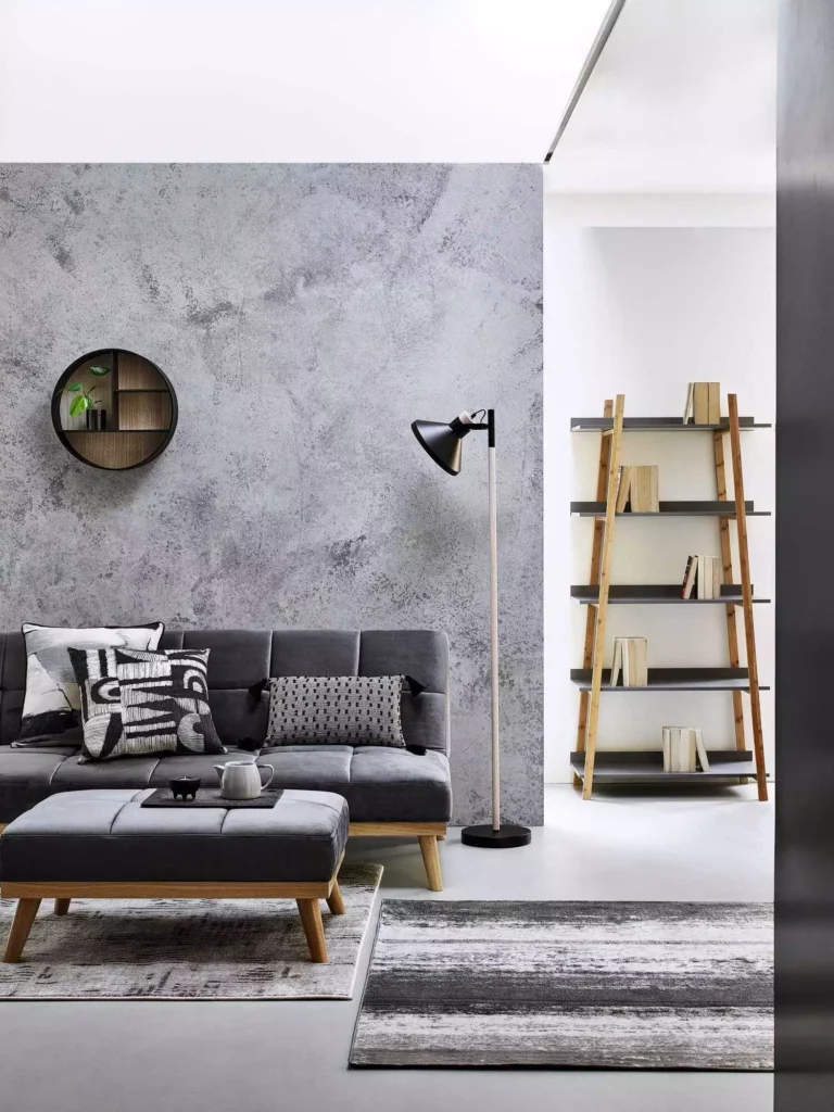 Textured concrete effect grey wall living room with charcoal sofa, ladder shelf and patterned rugs