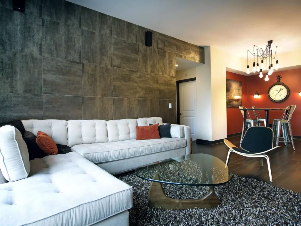 Textured gray tile accent wall behind white sectional sofa in living room