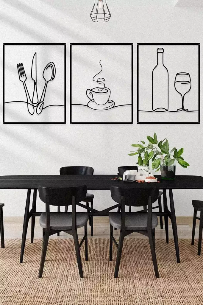 Three Black Metal Line Art Panels Of Cutlery, A Coffee Cup And A Wine Glass Create Modern Dining Wall Decor Above A Black Table