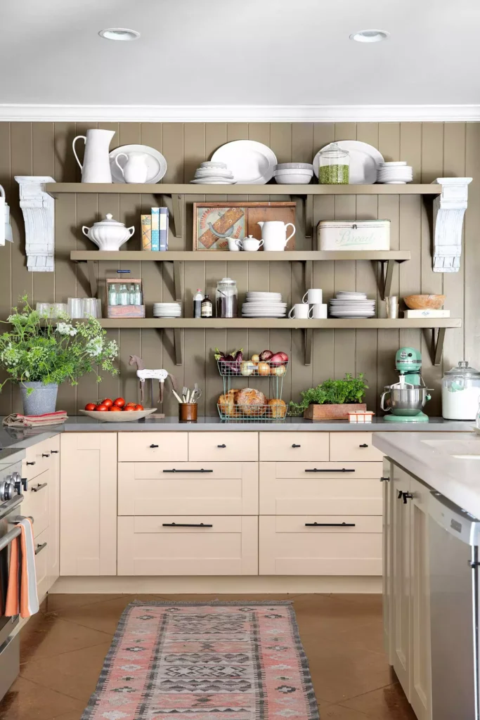 Three open shelves of white dishes on an olive paneled kitchen wall