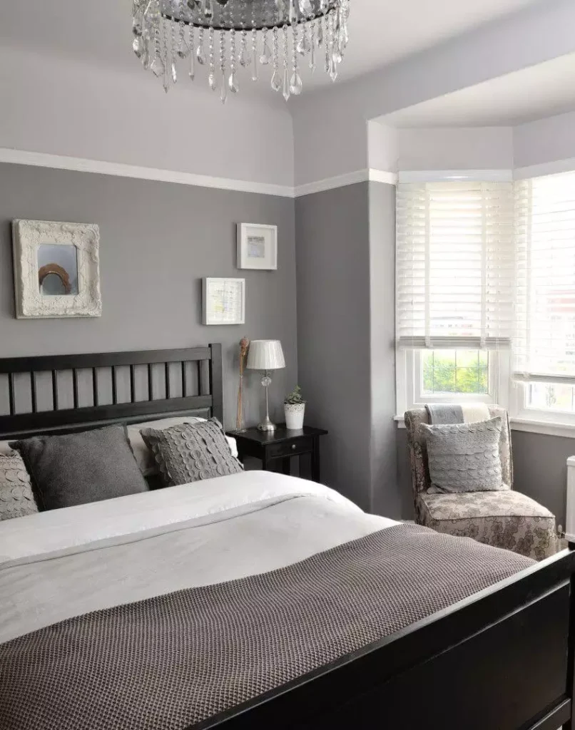 Two tone grey bedroom wall idea with black headboard, crystal chandelier and bay window seating