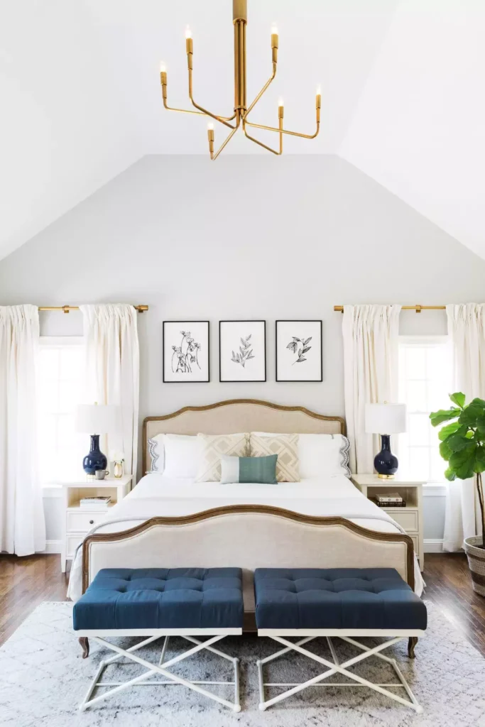 Vaulted bedroom with brass chandelier and framed botanical trio as over the bed wall decor