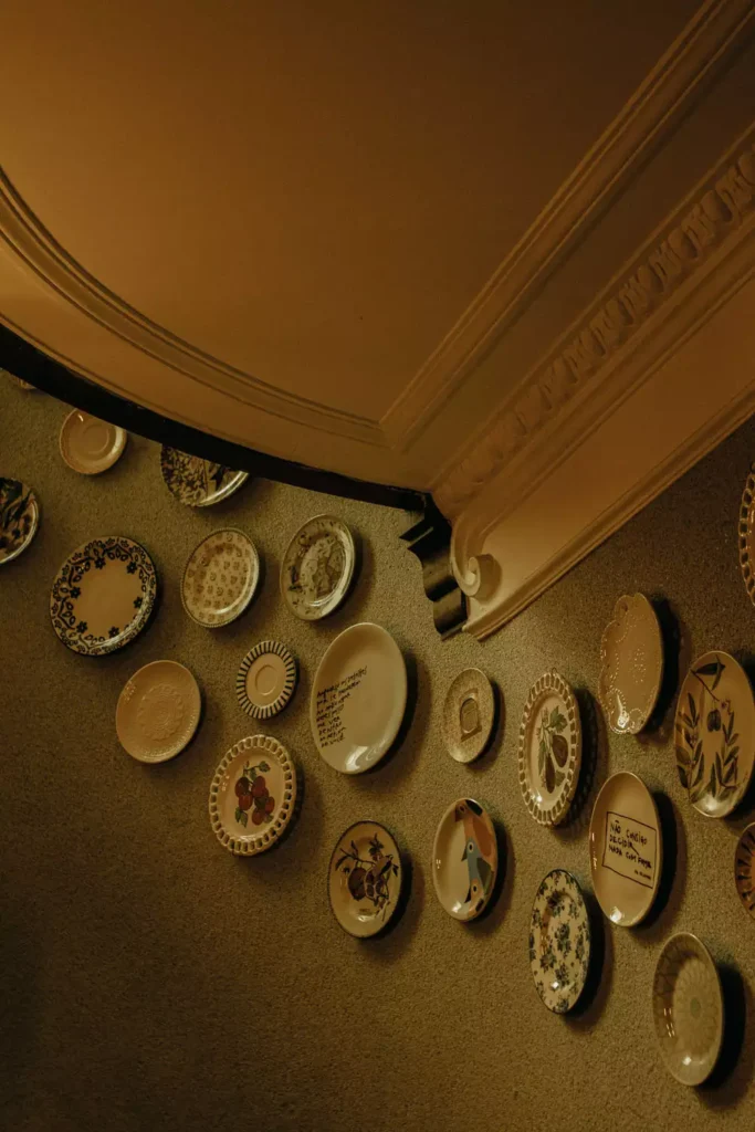 Vintage plate wall decor curving beneath an ornate ceiling molding