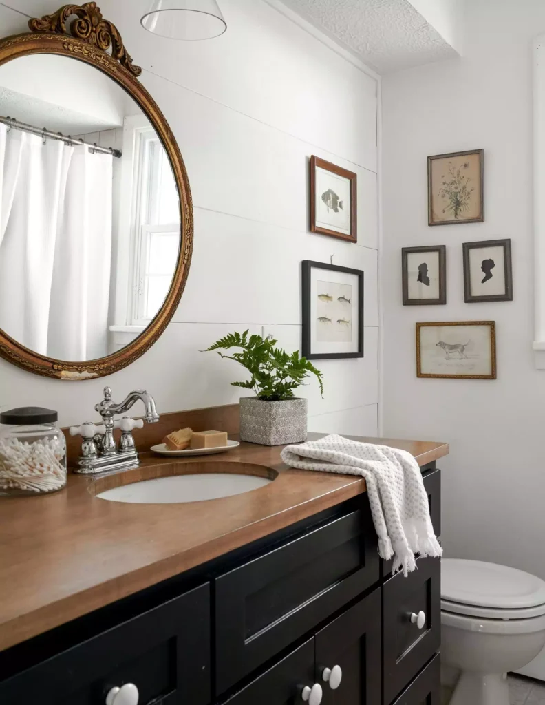 Vintage gold mirror and antique animal print gallery in a farmhouse bathroom