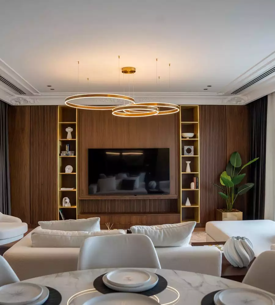 Walnut TV Wall Flanked By Gold Trimmed Shelves Under Circular Pendant Lights