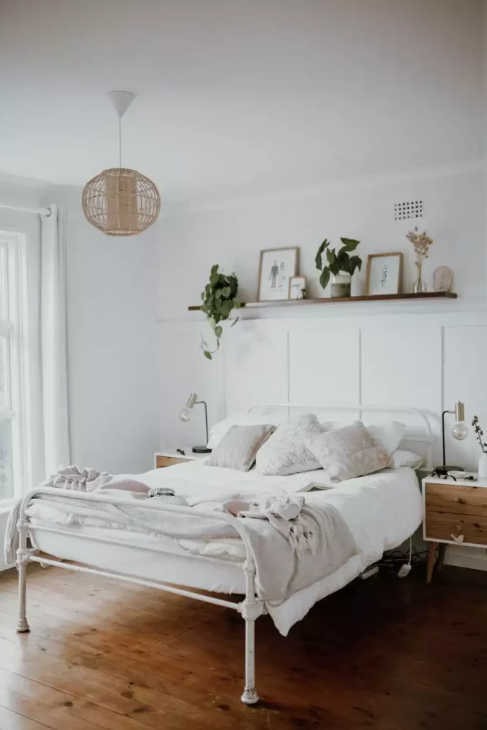 White Paneled Small Bedroom Wall Decor With A Floating Picture Shelf And A Rattan Pendant Light