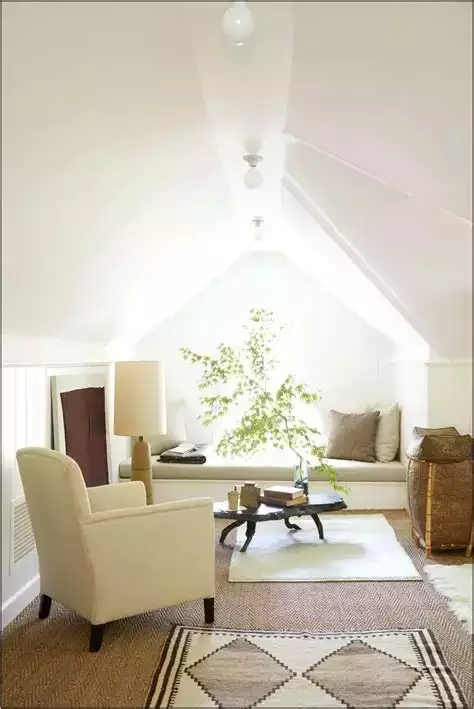 White attic nook, sloped ceiling, window daybed, woven rugs, cream armchair