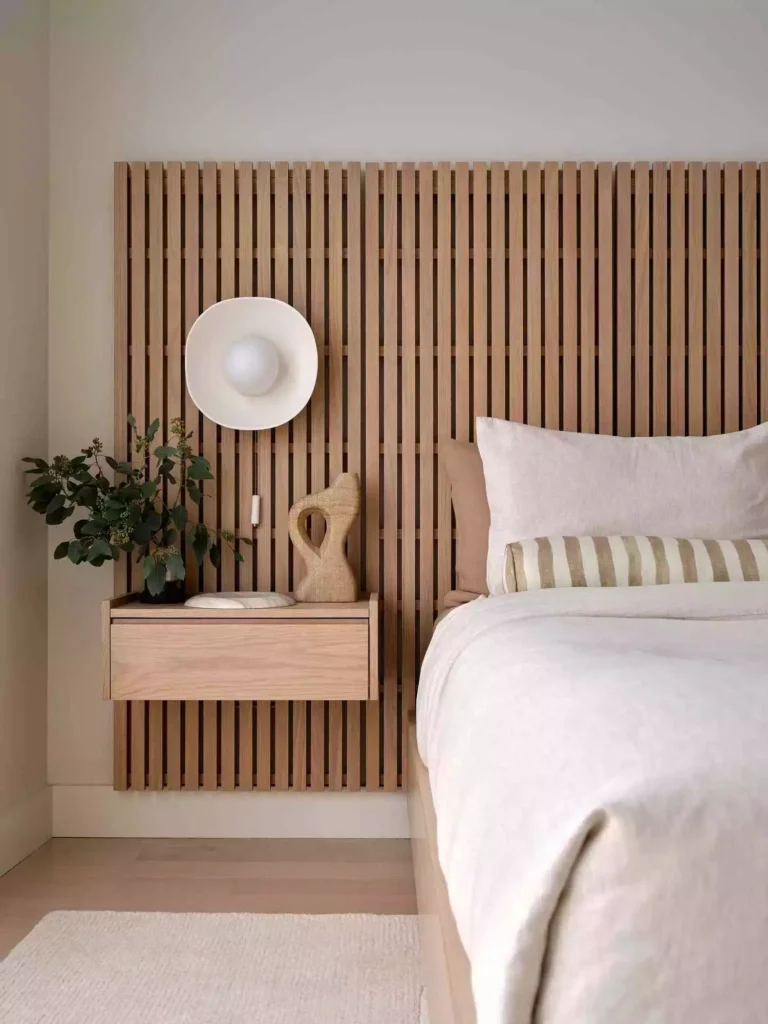 White bedroom with oak slat wall, floating nightstand, mushroom sconce, linen bedding
