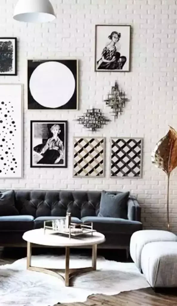White brick gallery wall, tufted gray sofa, marble table, gold leaf